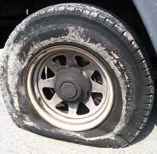 Help changing a flat tire - Does he really need *another* person to help change the car tire?